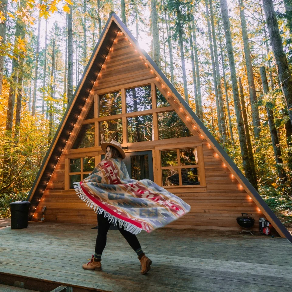 A wooden cabin in the forest and a figure in motion.